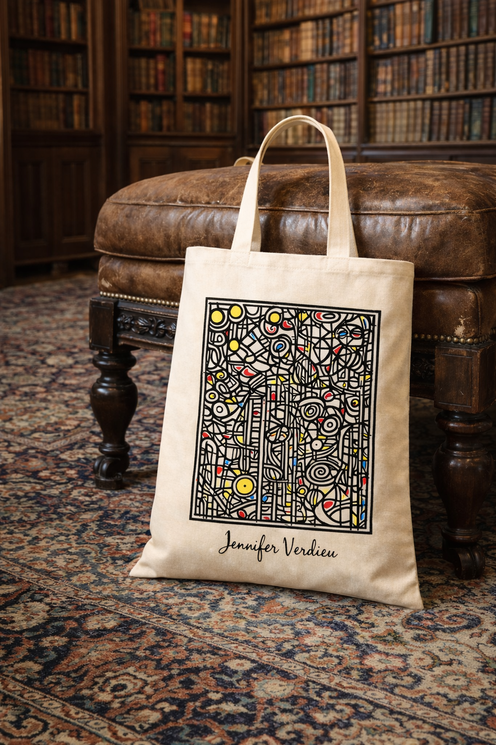 Beige tote bag with geometric design and text on a leather ottoman in a library setting